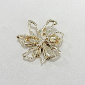 Detailed back view of golden floral brooch showing the pin clasp and hammered metal texture