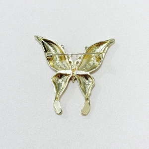Detailed back view showing the golden butterfly brooch pin clasp and textured metal surface