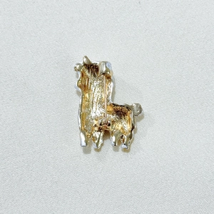 Macro view of the alpaca brooch back featuring brushed metal texture and safety pin clasp