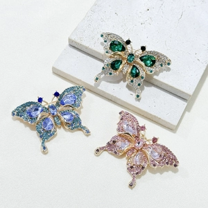 Detailed macro of crystal butterfly brooches in emerald, sapphire, and pink gemstone