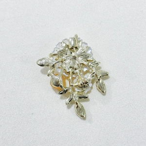 Detail view of the gold-tone metal back structure and pin lock of the daisy brooch