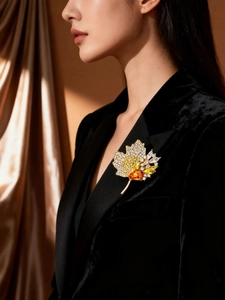 Detailed view of luxury maple leaf brooch with sparkling diamonds on black velvet suit