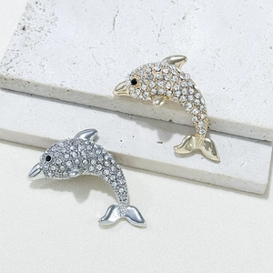 Broches dauphins exquises en or et argent avec strass sur un socle en pierre texturée blanc
