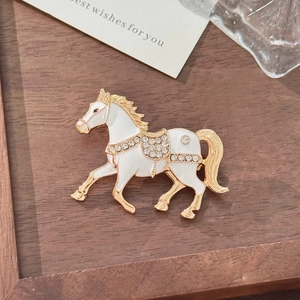 Exquisito broche de caballo dorado con esmalte blanco y detalles de cristal brillante