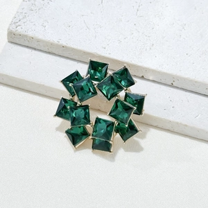 Elegant gold wreath brooch with square cut emerald crystals in a minimalist circle