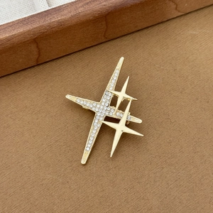 Macro shot of minimalist triple star brooch with rhinestones and polished gold finish