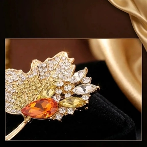 Macro detail of luxury maple leaf brooch with vibrant crystals on black velvet