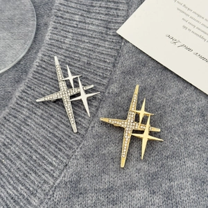 Close-up of gold and silver star brooches with rhinestones on grey knitwear