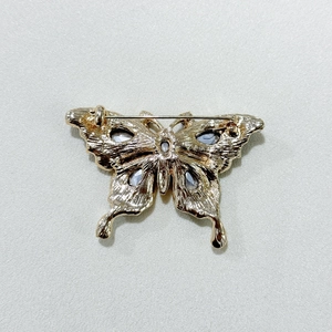 Detailed close-up of the butterfly brooch back showing golden texture and pin fastener