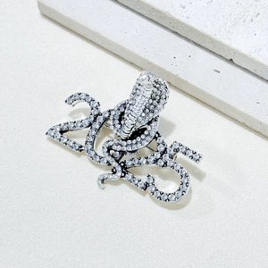 Detailed close-up of 2025 snake brooch featuring silver plating and white rhinestones
