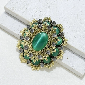 Vintage-Brosche im Barockstil mit grünem Katzenauge und Kristallen auf Goldbasis