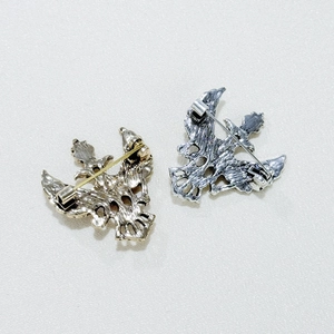 Detail view of the secure pin clasp on gold and silver eagle-shaped alloy brooches