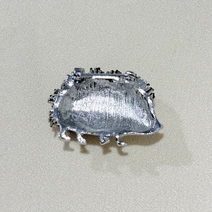 Detail view of the silver hedgehog brooch back showing the pin fastener and metal texture