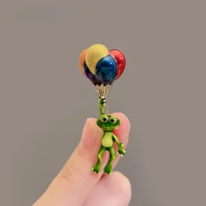 Détail d'une broche grenouille verte créative avec ballons colorés en émail à la main