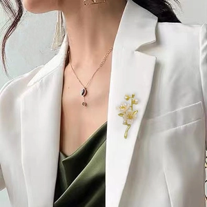 Detail of white jasmine flower brooch with gold buds on a white suit jacket lapel
