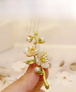 Macro detail of jasmine flower brooch with white petals, green enamel and yellow stones