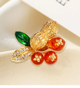 Detail of peanut and red fruit brooch with gold finish, green enamel leaf and crystals