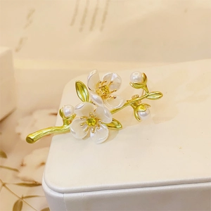 Detail of elegant jasmine flower brooch with white petals, pearls, and golden leaf branches