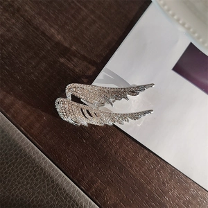 Close-up of sparkling silver angel wing brooch with detailed crystal pavé setting
