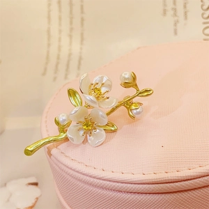 Exquisite jasmine flower brooch with white petals, gold stems and pearls on jewelry box
