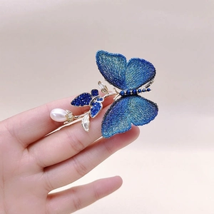 Détail d'une broche papillon brodée bleue vintage avec perles élégantes et strass brillants