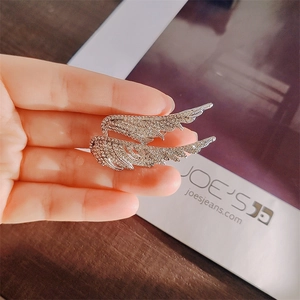 Detail shot of silver angel wing brooch with sparkling rhinestones held in hand