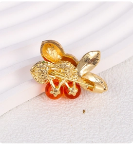 Detail view of gold metal brooch back with secure pin clasp and orange beads
