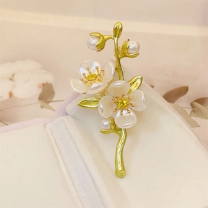 Detail of jasmine flower brooch with white petals, pearls, and green stem on jewelry box