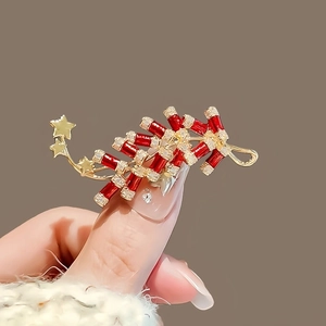 Détail d'une broche de Nouvel An chinois en forme de pétards rouges et étoiles dorées