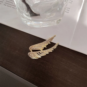 Detail of gold angel wing brooches with sparkling rhinestones on vintage background