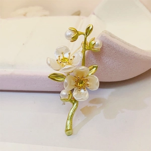 Macro detail of jasmine flower brooch with pearls and green leaves on a pink velvet box