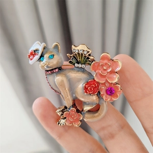 Détails d'une broche chat vintage avec fleurs en émail coloré et strass scintillants