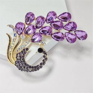 Macro shot of purple teardrop crystals and gold peacock brooch with sparkling rhinestones