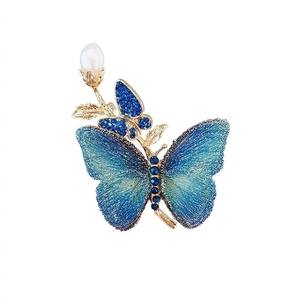 Détail de broche papillon vintage avec broderie bleue et pendentif en perle d'eau