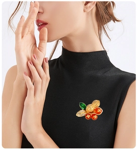 Detailed view of Persimmon and Peanut brooch with rhinestones on a black garment