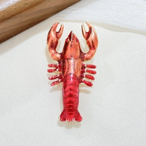 Macro shot of red enamel lobster brooch with gold metal and rhinestone details