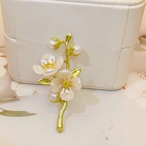 Detail of jasmine flower brooch with green vine, white enamel petals and pearl accents