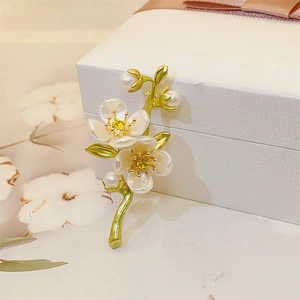 Detail of jasmine flower brooch with green enamel leaves and white pearls on a gift box