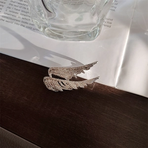 Macro shot of silver angel wing brooch with sparkling rhinestones on vintage background