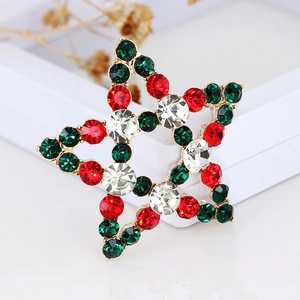 Detail of star brooch with red and green crystals on a gold alloy holiday base