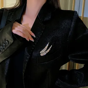 Silver angel wing brooch with sparkling rhinestones pinned on a black suit lapel