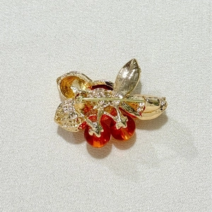 Macro shot of gold-plated metal base and secure safety pin buckle on cherry brooch