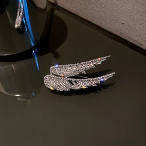 Elegant silver angel wings brooch encrusted with white crystals on a reflective surface