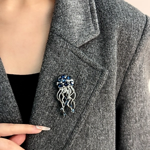 Détail d'une broche méduse de luxe avec cristaux bleus sur un revers de manteau gris
