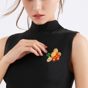 Creative peanut and persimmon brooch with gold finish and rhinestones on black sweater