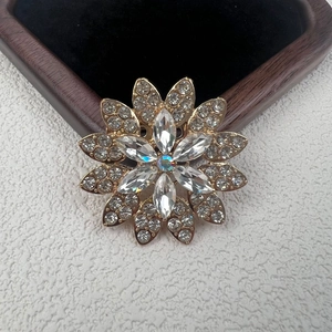 Primer plano de broche floral dorado con brillantes diamantes de imitación y circonitas