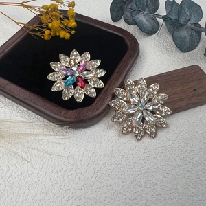 Elegantes broches de flores doradas con diamantes de imitación sobre base de madera