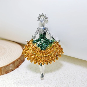 Macro detail of ballerina brooch featuring green and orange crystals in silver plating