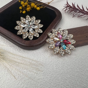 Elegantes broches florales de pedrería blanca y multicolor sobre un fondo rústico natural
