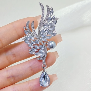 Détail de broche ailes d'ange avec zircons clairs, perle grise et pendentif en goutte